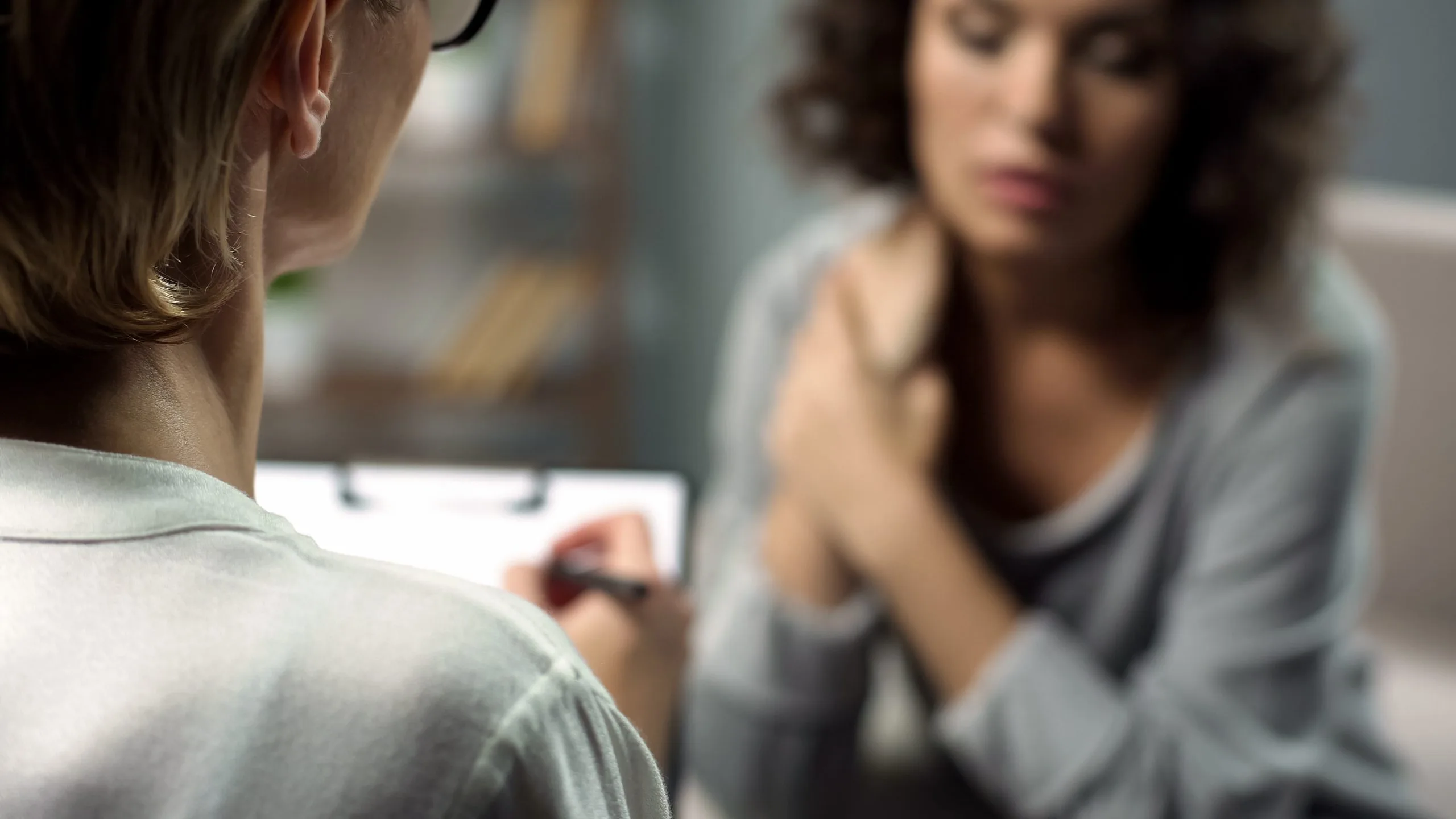 Female psychologist listening to young lady during personal session, depression