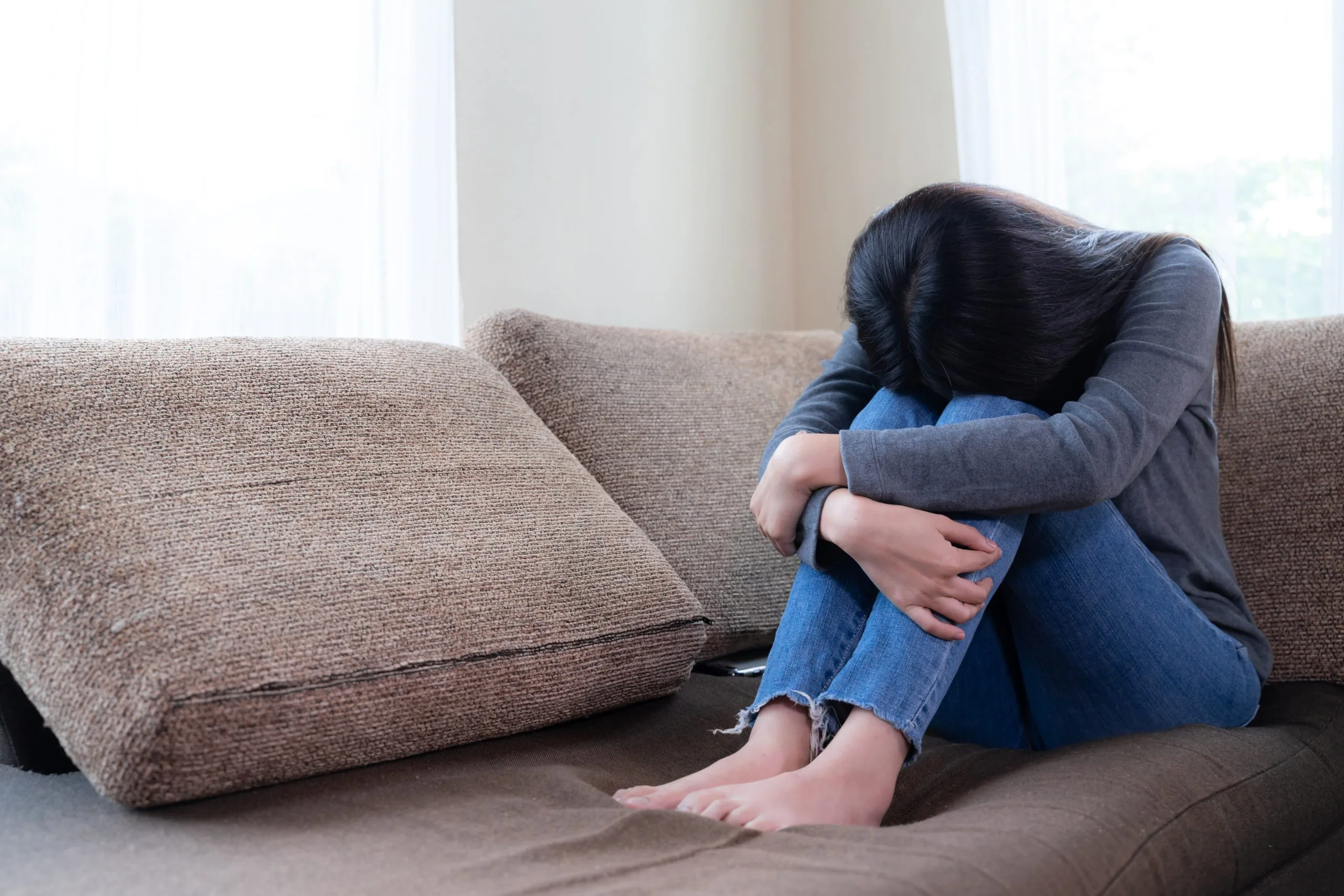 Unhappy asian pretty young woman siting alone on couch with feeling sadness